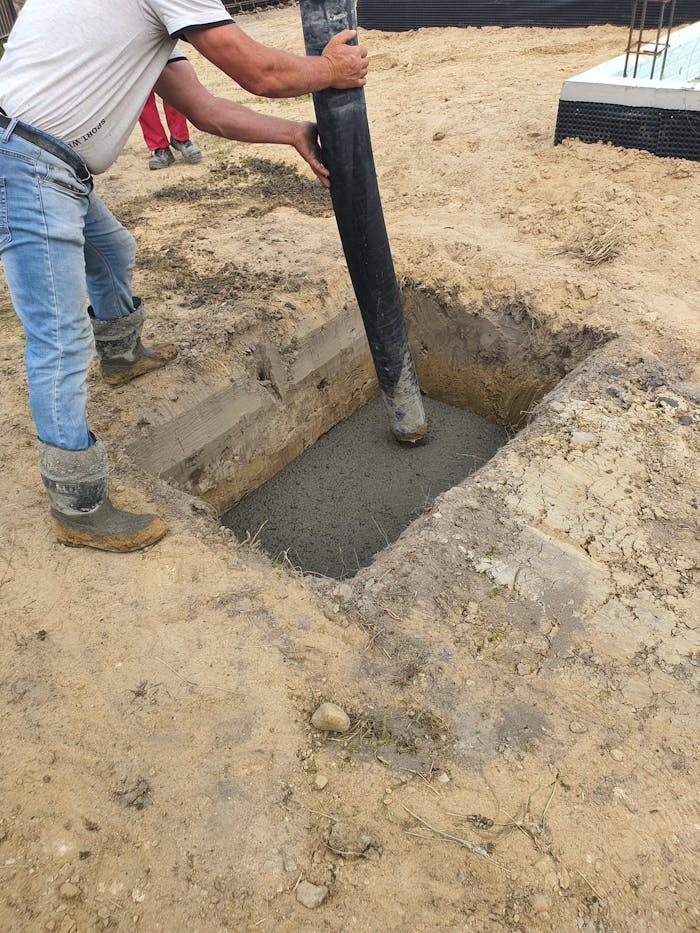 Worker using hose to pour concrete into foundation at site in Poland.